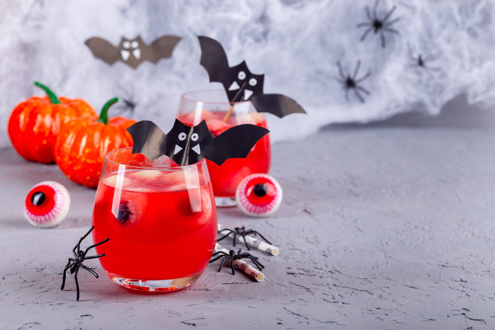 Halloween cocktail with red bubble drink and eyes made from lychee and blueberry, Halloween decoration on background, horizontal, copy space